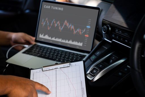 A close-up of an auto mechanic working on a laptop, analyzing car tuning data.