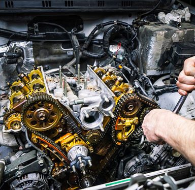 A close-up of an auto mechanic holding a tool while working on an engine block.