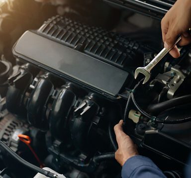 A close-up of an auto mechanic holding a wrench while fixing a car engine.