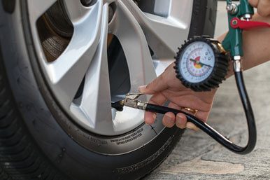 A close-up of a man checking tire pressure using a tire pressure gauge.